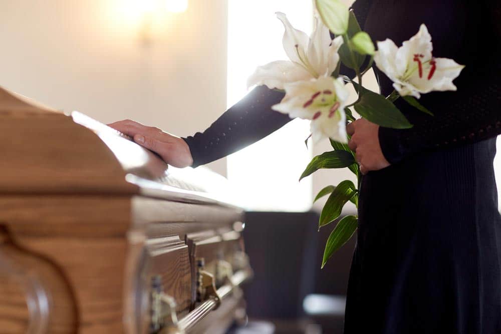 Woman Holding White Flowers On A Funeral