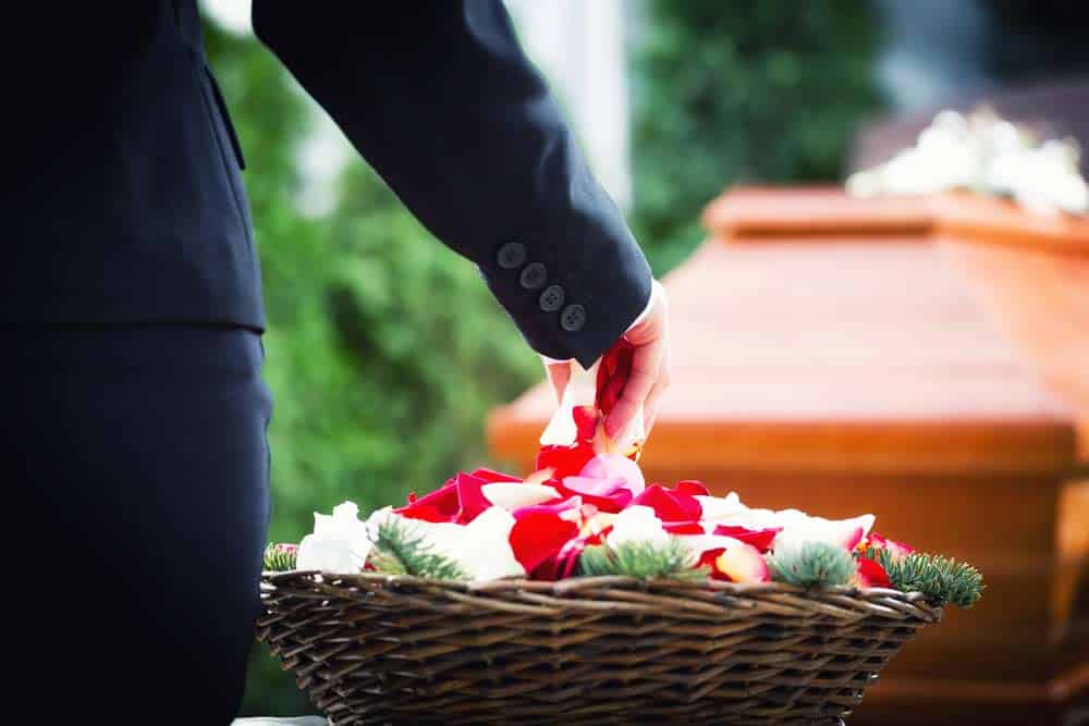 Woman On Funeral Putting Rose Petals On Coffin